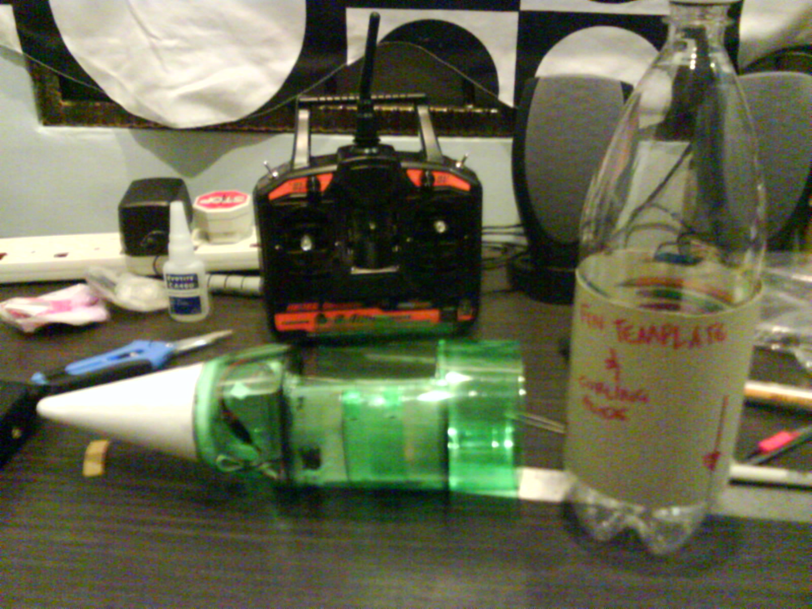 blur picture taken with the cameraphone (due to bad lighting)<br /><br />in the background, the TX (transmitter)<br /><br />i used the &quot;throttle cut&quot; switch to activate the servo motor. it's plugged into the RX's channel 3.
